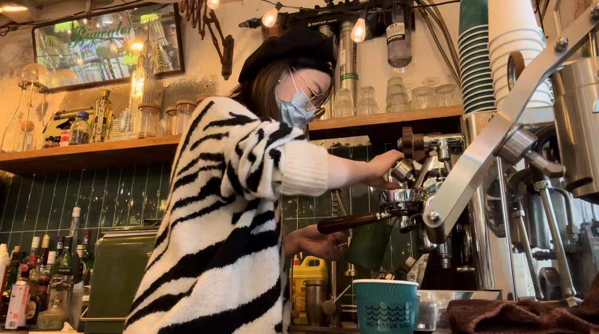 Yating making coffee behind the counter at a café