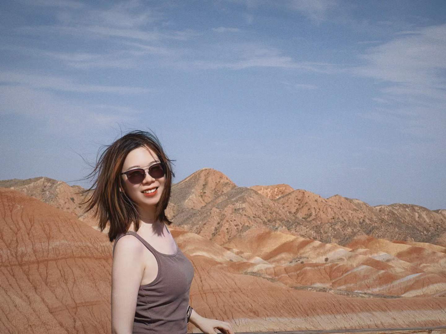 Yating smiling in front of colorful mountain ridges